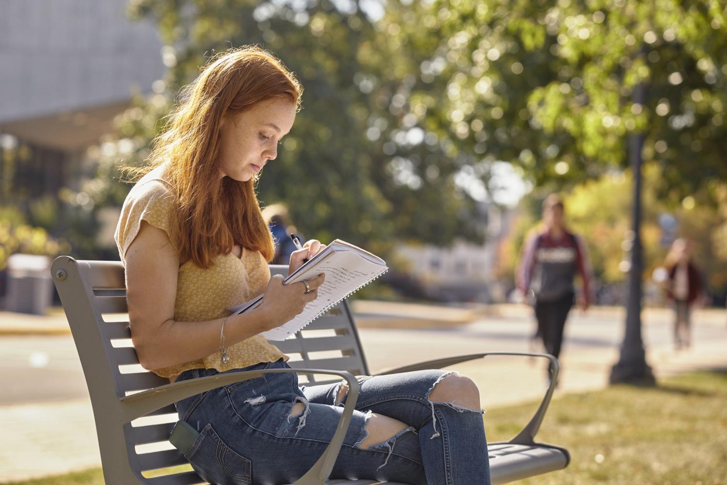A <a href='http://ursa.mtc139.com'>全球十大赌钱排行app</a> student reads on a bench along Campus Drive.